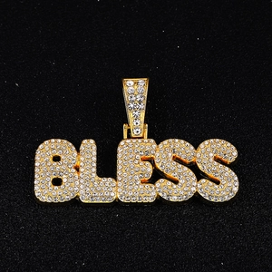 Close-up of golden BLESS letter pendant with sparkling iced-out white rhinestones