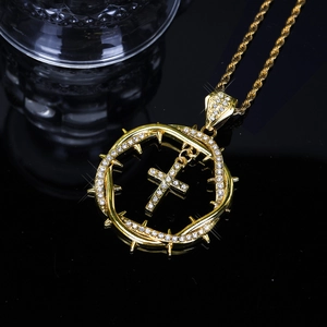 Close-up of golden intertwined thorn cross pendant with white zircon inlays on rope chain