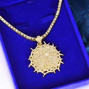 Macro detail of iced-out gold cross pendant with thorn crown in blue velvet box