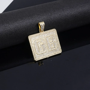 Dettaglio del ciondolo quadrato dorato con lettere GB e cristalli in stile hip hop
