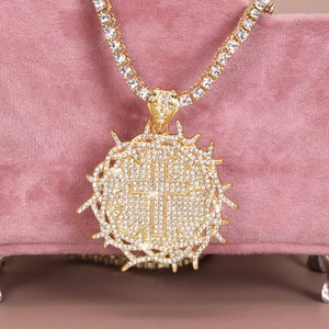 Macro detail of iced-out thorn cross pendant with crystals on pink velvet stand