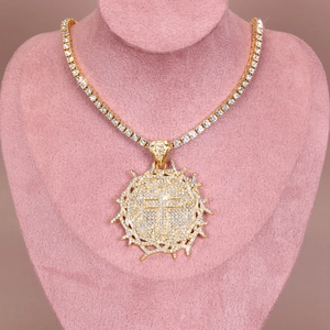 Detailed macro view of iced-out thorn cross pendant with gold tennis chain