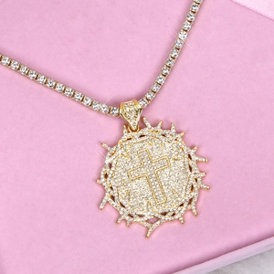 Macro detail of gold thorn cross pendant with sparkling rhinestones on a tennis chain