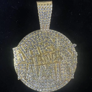 Macro view of gold iced out Money and Family letter pendant with encrusted crystals