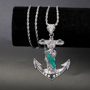 Macro shot of silver anchor pendant with San Judas image and green enamel details