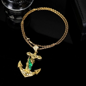 Detailed macro of a gold-plated anchor cross pendant with green accent and rhinestones