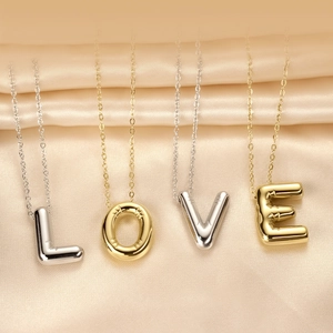 Polished stainless steel LOVE letter pendant necklace set on smooth silk background