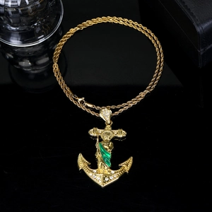 Detail of gold anchor pendant with San Judas image and green enamel over black reflection