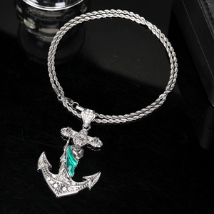 Macro shot of silver anchor pendant with green portrait and white rhinestones on twist chain
