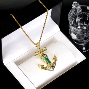 Macro detail of gold anchor pendant with Saint Jude figure and glittering cubic zirconia