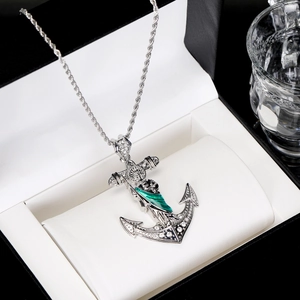 Detail of silver anchor pendant with green enamel and clear crystals on a twist chain