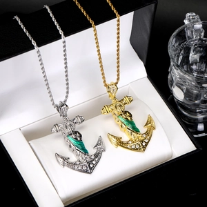 Detail of gold and silver anchor pendants with green religious reliefs and zircons