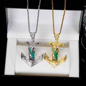 Detail of silver and gold anchor pendants with green enamel and white diamonds on chain