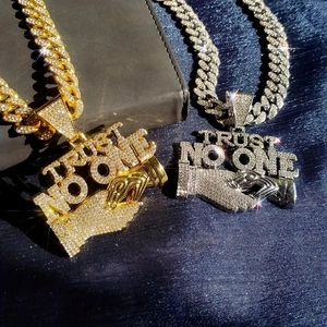 Detailed close-up of iced-out Trust No One pendant with a heavy Cuban chain in gold
