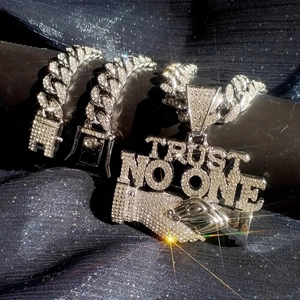Detail of silver iced-out Cuban chain set with 'Trust No One' pendant on velvet