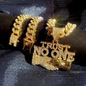 Close-up of gold iced out Cuban link chain and Trust No One pendant with stones