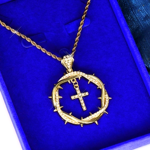 Detail of hip hop gold thorn circle cross pendant with rhinestones on blue velvet