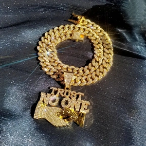 Macro shot of gold-plated iced-out Cuban chain and Trust No One pendant detail