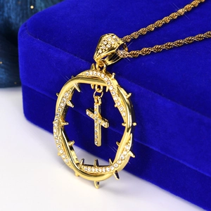 Close-up of a gold-toned hip hop crown of thorns and cross pendant on blue velvet
