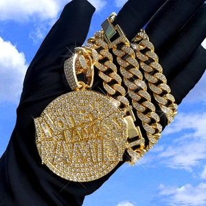 Golden Cuban chain with iced-out Land of the Free round pendant against a blue sky