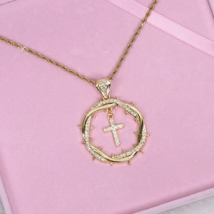 Gold hip hop necklace with iced-out thorn circle and cross pendant on pink velvet