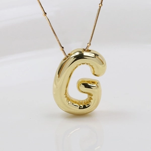 Makroaufnahme vom 3D-Bubble-Buchstaben G Anhänger mit Goldfinish und Perlenkette