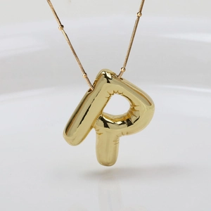 Detail eines goldenen Buchstaben-P-Anhängers mit Ballontextur und Perlenkette für Damen
