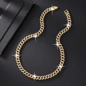 Macro detail of gold-plated double-row crystal Cuban link chain on black texture