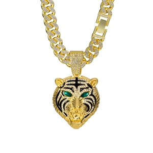 Détail macro du pendentif tigre doré avec cristaux et yeux verts sur chaîne cubaine