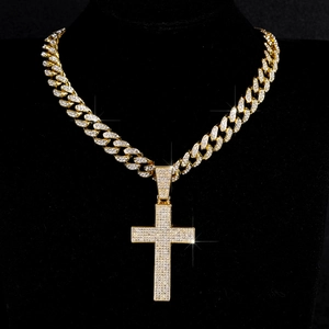 Detail van hiphop gouden Cubaanse schakelketting met grote kruishanger vol zirkonia
