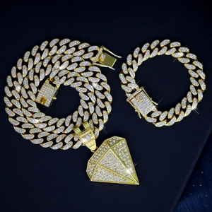 Close-up of gold iced-out Cuban link chain set with large diamond-shaped pendant on black