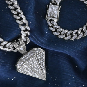Silver iced out Cuban link chain with a large diamond shaped pendant in hip hop style