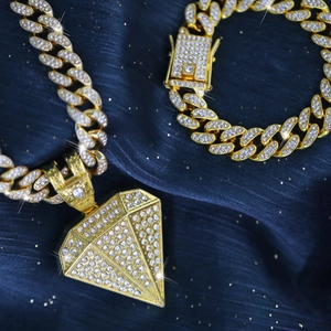 Detail of gold Cuban link chain set with sparkling diamond pendant on blue silk