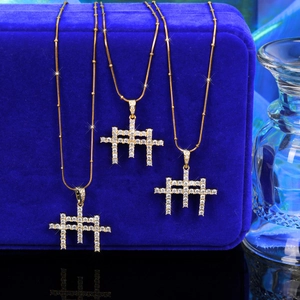 Détail de trois colliers à billes dorés avec pendentifs croix géométriques en zircon