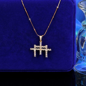 Gros plan du pendentif croix dorée avec zircons sur un fond en velours bleu marine