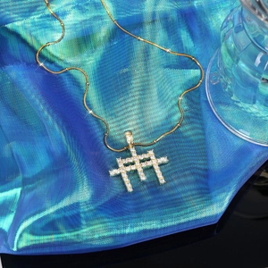 Gros plan d'un pendentif croix hip hop doré avec zircons sur tissu bleu brillant
