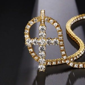 Close-up of iced out cross pendant with sparkling rhinestones on golden tennis chain