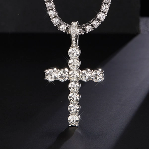 Macro shot of silver hip hop cross pendant with large rhinestones on a tennis chain