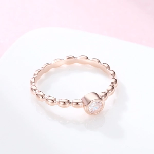 Bague élégante en or rose avec anneau à bulles et pierre ronde sertie clos sur blanc