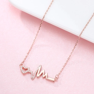 Roségoldene S925 Silber Herzschlag-Kette mit weißen Kristallen auf rosa Hintergrund