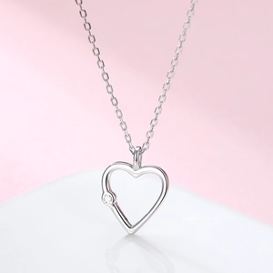 Macro shot of silver hollow heart pendant necklace with a sparkling round zircon stone