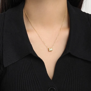Close-up of gold cylinder pendant necklace with square cubic zirconia on a model