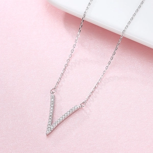 Polished 925 sterling silver V-shape pendant necklace with cubic zirconia on pink background