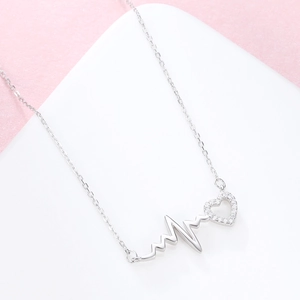 S925 sterling silver heartbeat necklace with heart-shaped diamond pendant on pink background