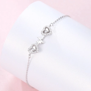 Macro detail of s925 silver double heart bracelet with pavé stones and heartbeat symbol