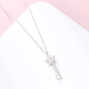 Collier avec pendentif clé en argent massif S925 et cristaux sur un fond rose tendre