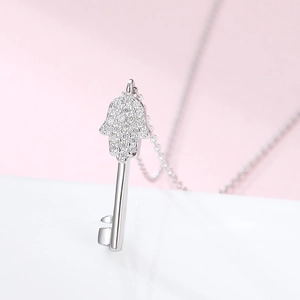 Macro detail of Hamsa hand and key pendant encrusted with white cubic zirconia stones