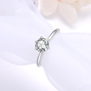 Macro view of six-prong setting with a brilliant round cut moissanite on a silver ring