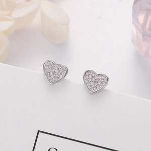 Macro shot of silver heart earrings with pink pavé zircon stones on white stand
