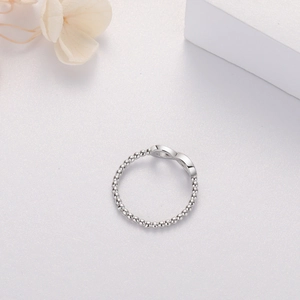 Detailansicht des Unendlich-Symbol-Rings mit Perlenstruktur auf minimalistischem Hintergrund